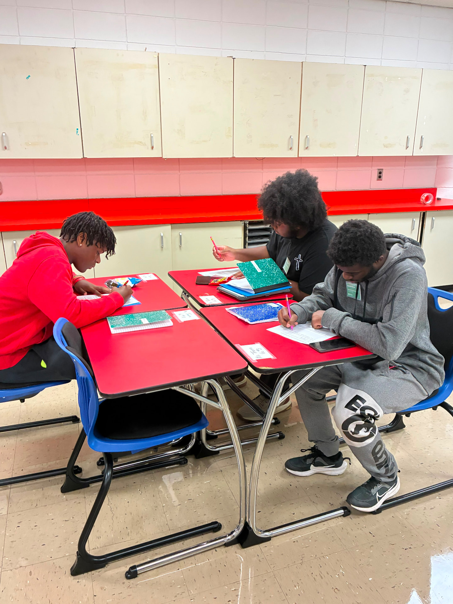 Three young scientists working together on written activities in a science classroom